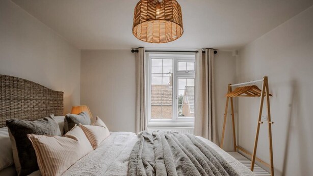 A bedroom with a bed, a hanging light fixture, a window, and a wooden easel. - Coastal/petsok/kingbed/wifi/garden (Driffield)
