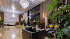 A modern lobby with a marble floor, leather sofas, a chandelier, and a reception desk with 'Tong Qian Wan' signage. - TongQianWan Hotel (Xiangshan)