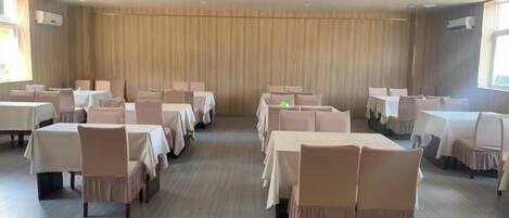 Une salle de conférence dotée de plusieurs tables et de nombreuses chaises, disposées en rangées.