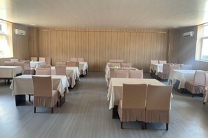 Un salón de conferencias con varias mesas y sillas dispuestas en filas.