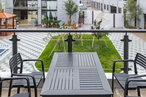 A balcony with a table and chairs, overlooking a checkered pavement and a green lawn. - TongQianWan Hotel (Xiangshan)
