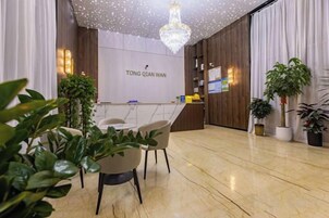 Una zona de recepción con suelo de mármol, un mostrador de recepción y plantas en macetas.