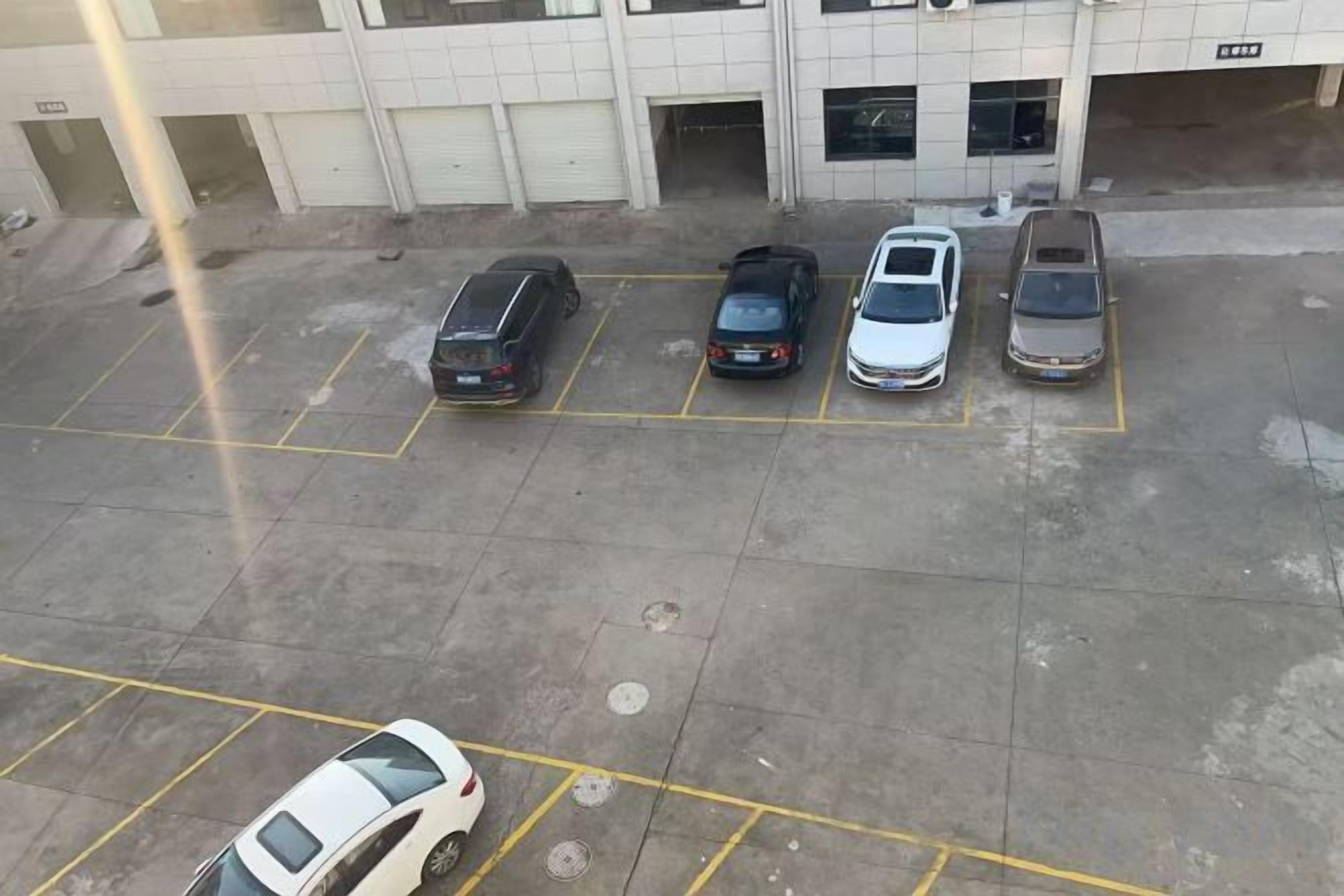 A parking lot with five cars parked in designated spaces.