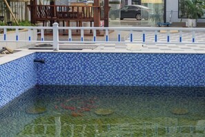 A swimming pool with a tiled edge and a white fence. - TongQianWan Hotel (Xiangshan)
