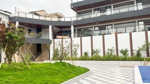 A modern multi-story building with a courtyard featuring a checkered pathway and green grass. - TongQianWan Hotel (Xiangshan)