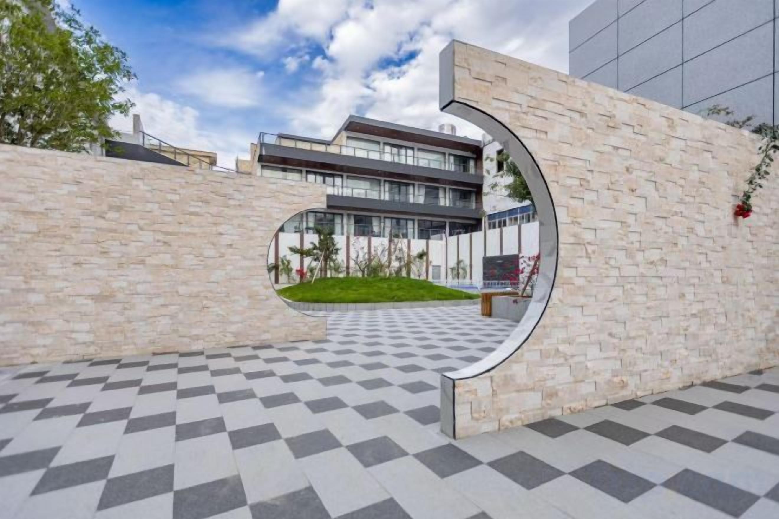 A modern building with a checkered floor pattern and a circular cut-out in the wall.