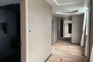 Pasillo de hotel con alfombra estampada, puertas y una lámpara en el techo.