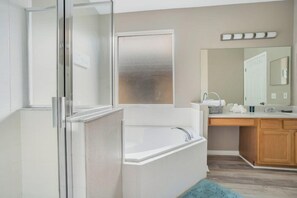 Een moderne badkamer met een douchecabine van glas, een vrijstaand bad, een wastafel met spiegel en een handdoekhouder.