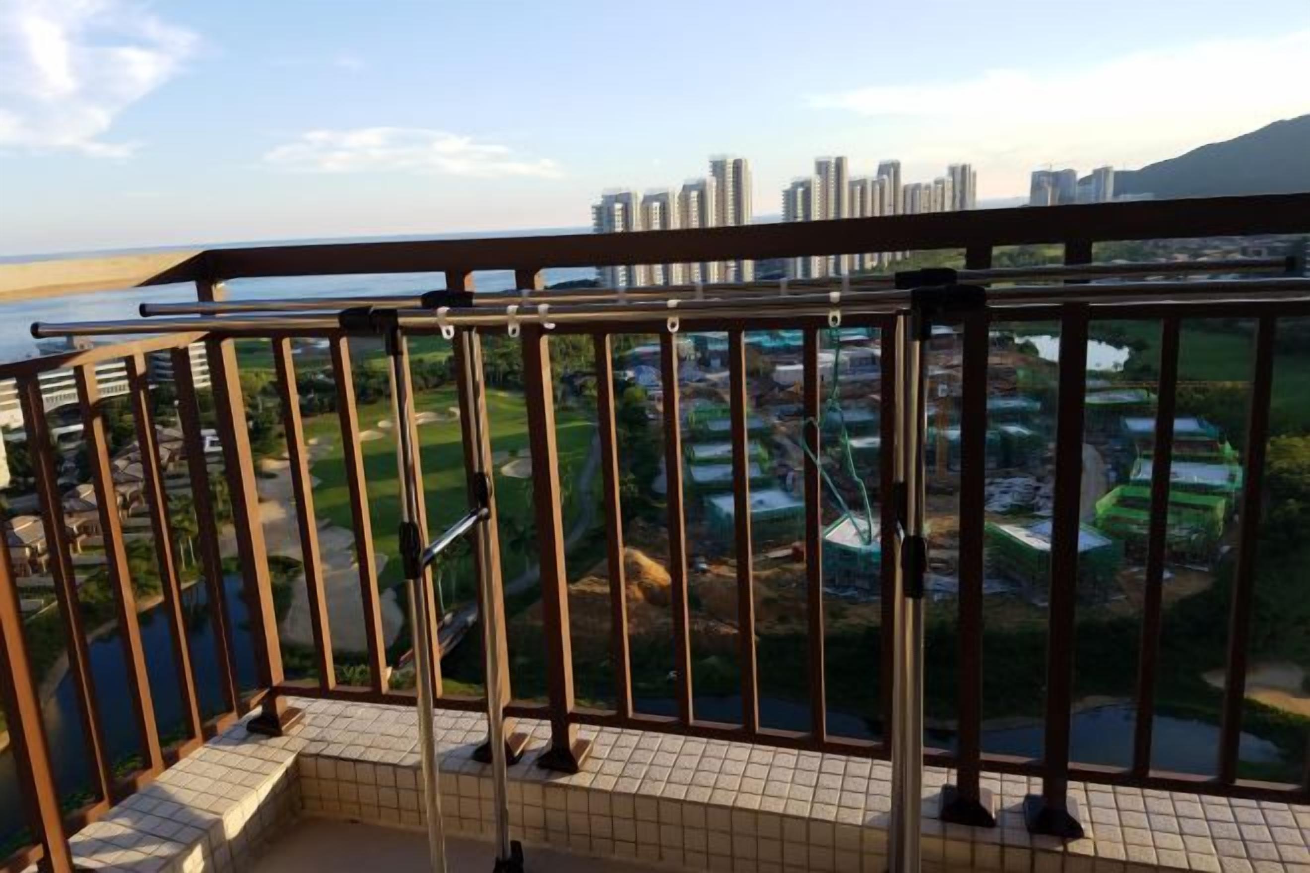 Ein Balkon mit Metallgeländer, der auf einen Wohnbereich mit Häusern und einem Gewässer blickt.