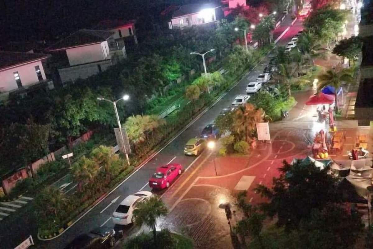 Straßenansicht bei Nacht mit parkenden Autos, Straßenlaternen und Gebäuden.