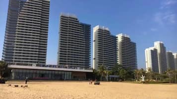Ein Hotel direkt am Strand mit Hochhäusern, Sandstrand und Palmen.