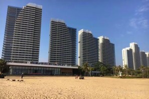 A beachfront hotel with high-rise buildings, sandy beach, and palm trees. - Haizhimeng Luxury Holiday Apartment Yangjiang Hailing Island Shili Yintan (Yangjiang)