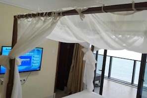 A room with a bed, a television, and a view of the sea. - Haizhimeng Luxury Holiday Apartment Yangjiang Hailing Island Shili Yintan (Yangjiang)