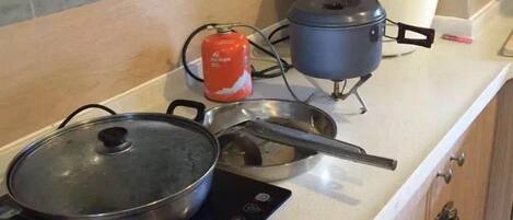 A kitchen with a stove, pots, and a rice cooker on the countertop.