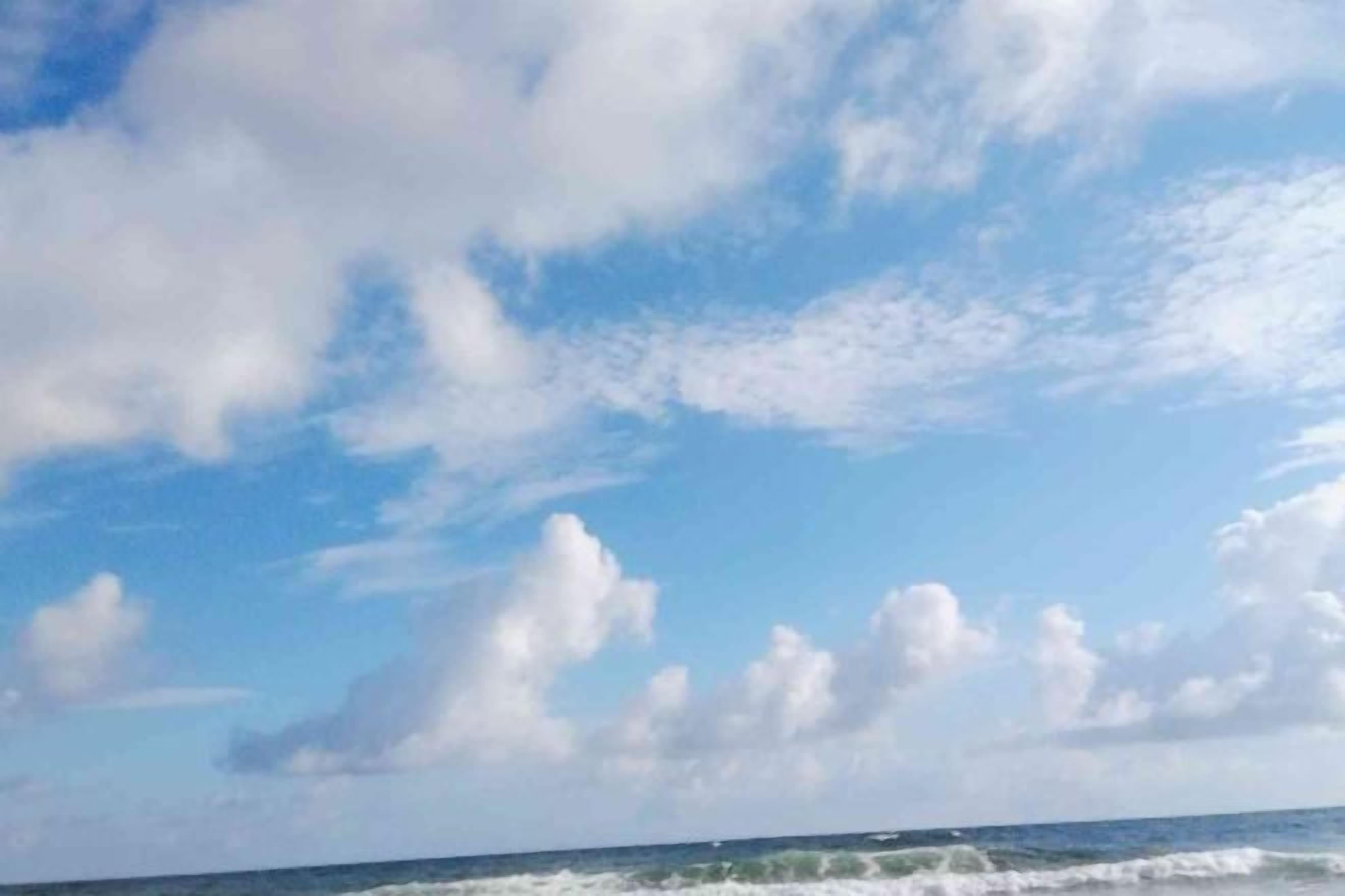 Un ciel dégagé avec quelques nuages épars au-dessus d’une étendue d’eau.