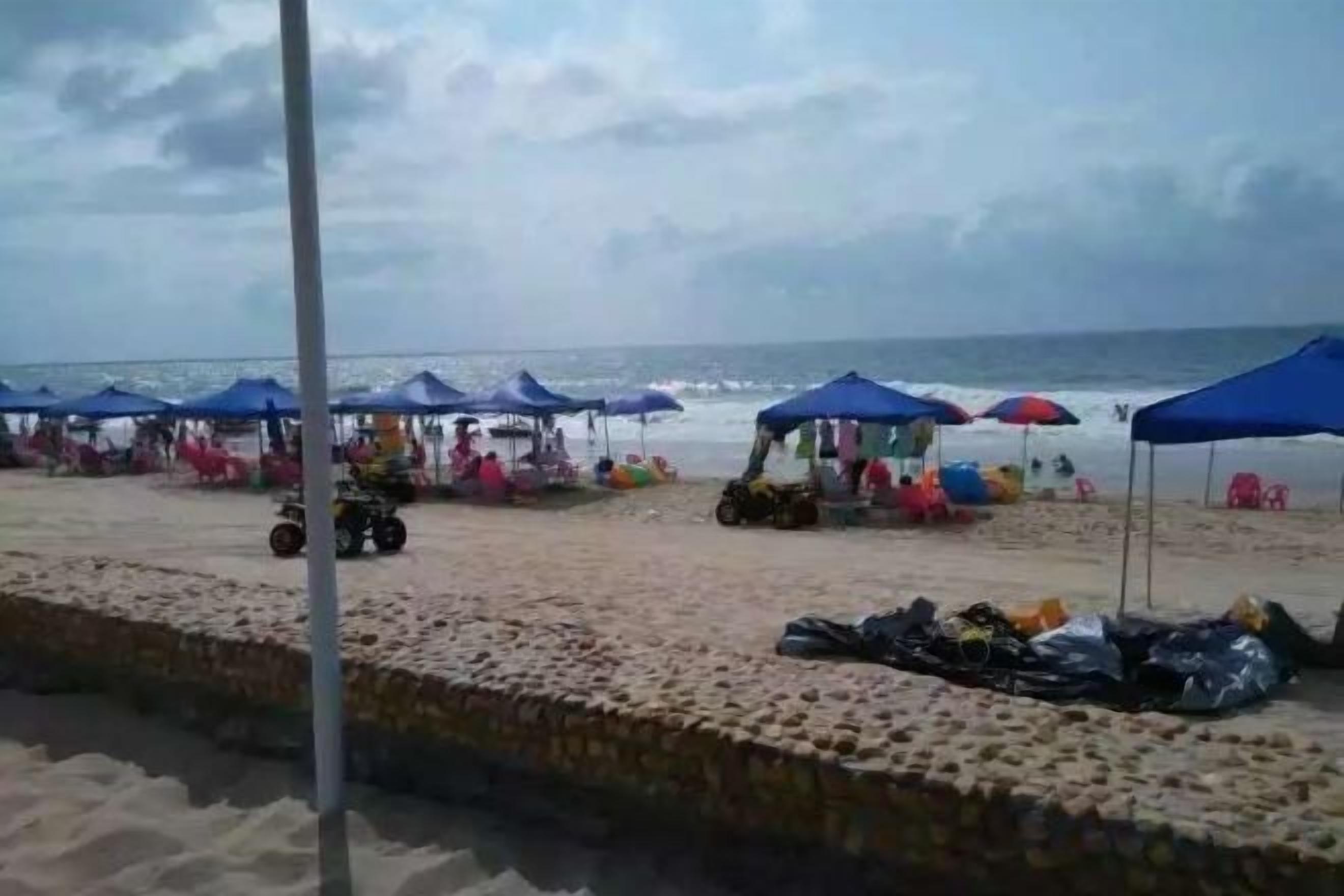 Una playa con sombrillas y sillas, una orilla arenosa y una masa de agua.