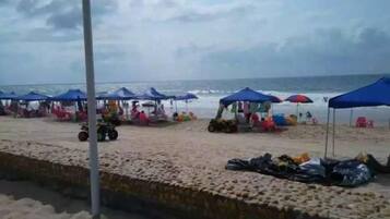 Una playa con sombrillas y sillas, una orilla arenosa y una masa de agua.