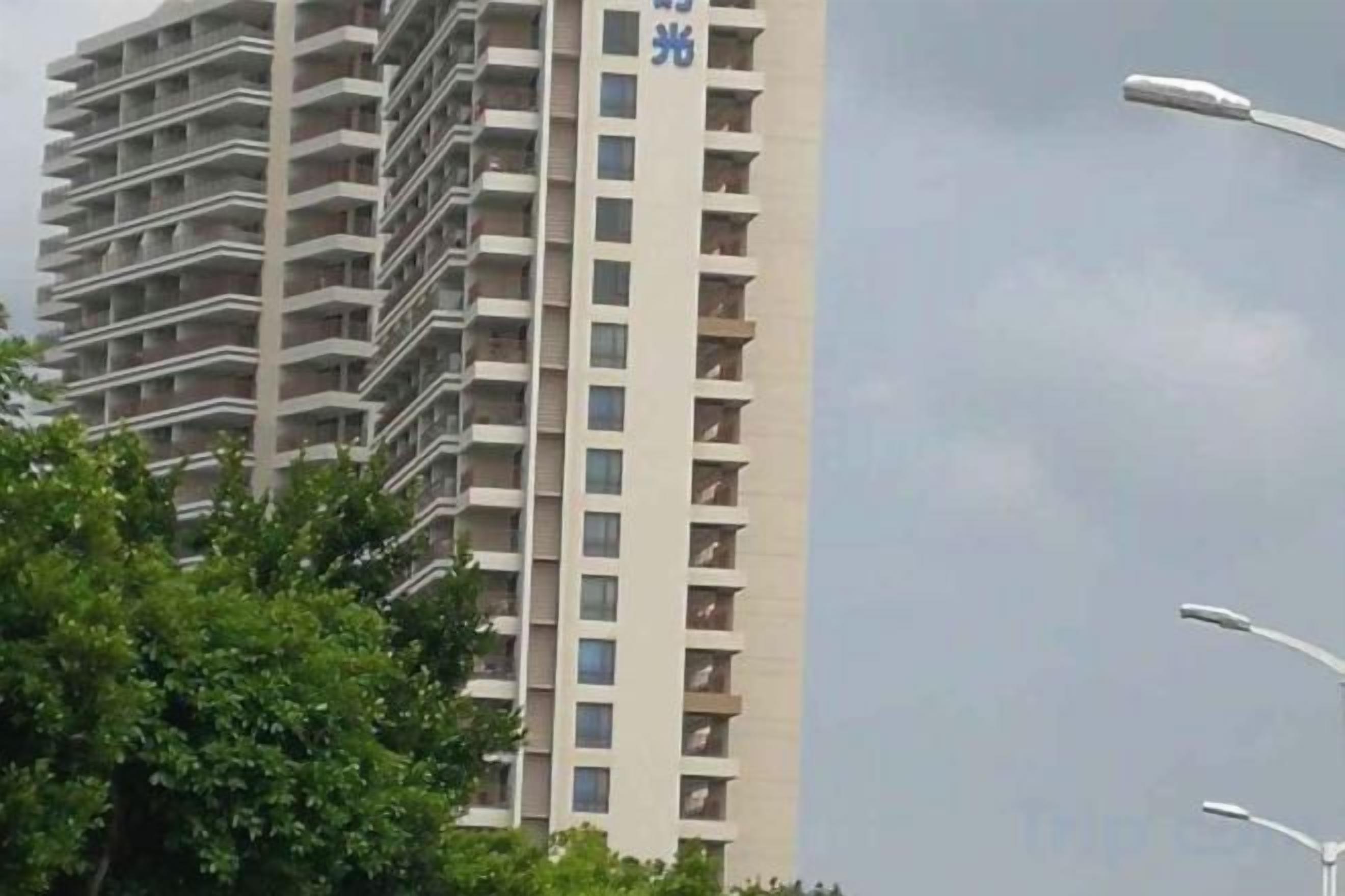 A high-rise building with multiple balconies and a clear sky.