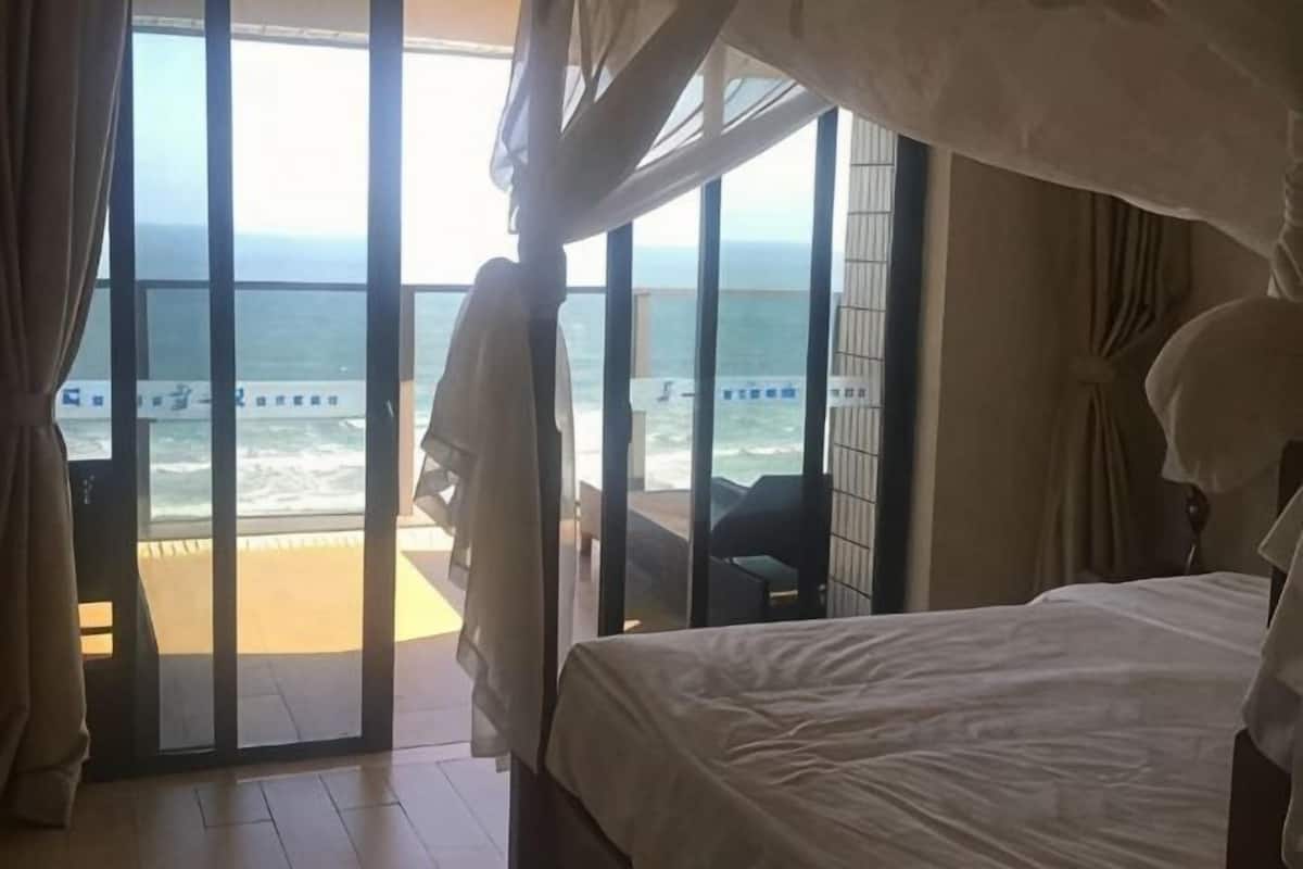 Ein Schlafzimmer mit einem großen Bett, Meerblick und einem Balkon mit einem Sessel.