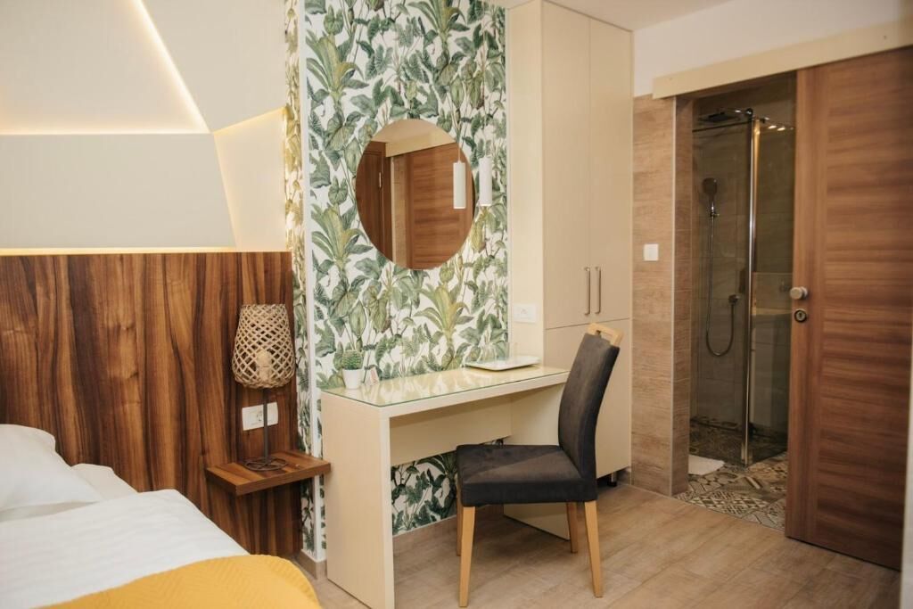 A hotel room with a bed, a desk with a chair, a shower, and a wardrobe.