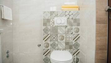 A bathroom with patterned tiles, a toilet, and a towel rack.