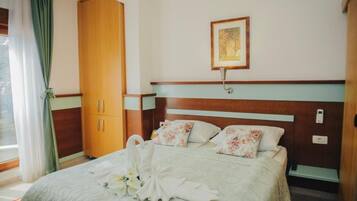 A hotel room with a bed, a wardrobe, a wall-mounted light, and a framed picture.