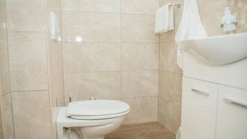 Een badkamer met toilet, wastafel en douchehoek.