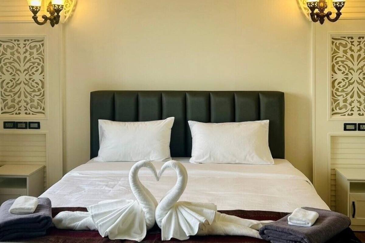 Une chambre d’hôtel avec un grand lit, des panneaux muraux décoratifs et deux lampes fixées au mur.