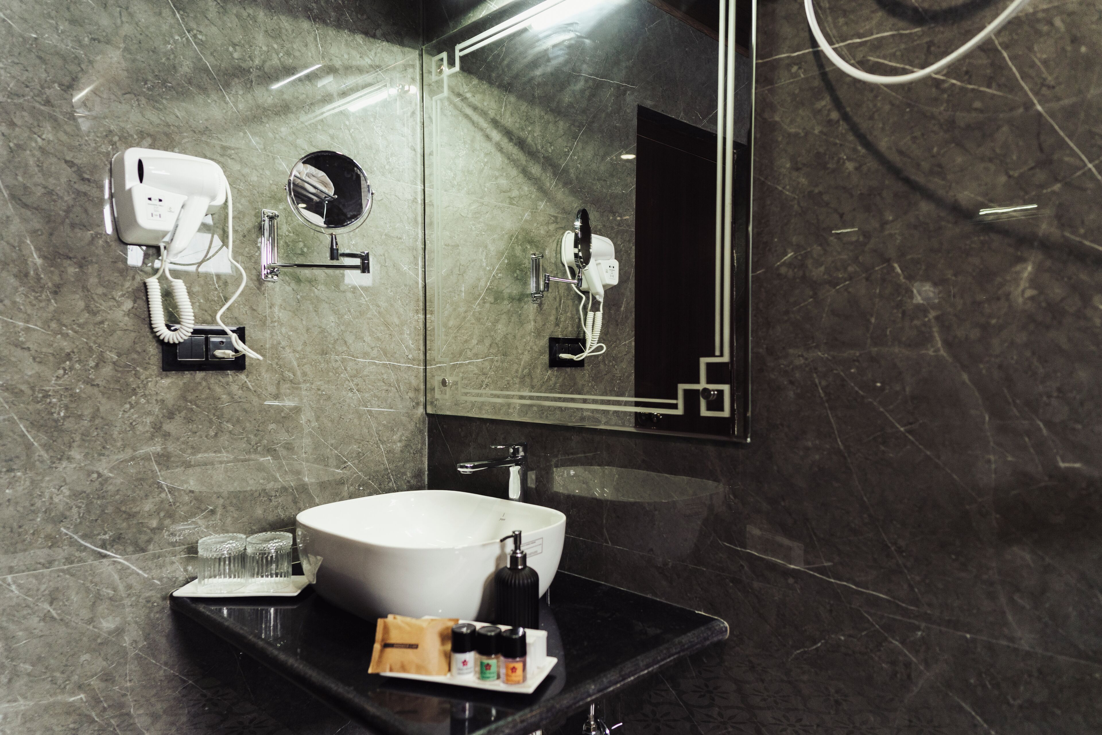 A modern bathroom with a large white sink, a mirror, a hairdryer, and a towel rack.