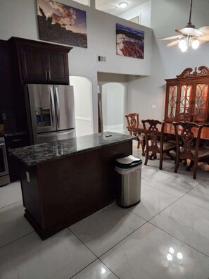 Enjoy meals in the kitchen with a central island, stainless steel appliances, and a dining area with chairs and a cabinet.