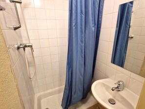 Un baño con ducha, lavabo y espejo.