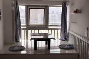 A room with a window, a table, and a bench. - Kaixuan Shidai Family Apartment (Dalian)