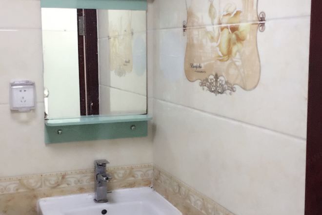 A bathroom with a sink, mirror, and decorative wall tiles.