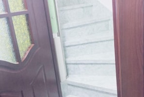 Eine Holztür mit Glasfenster, die zu einer Treppe mit weißen Stufen führt.