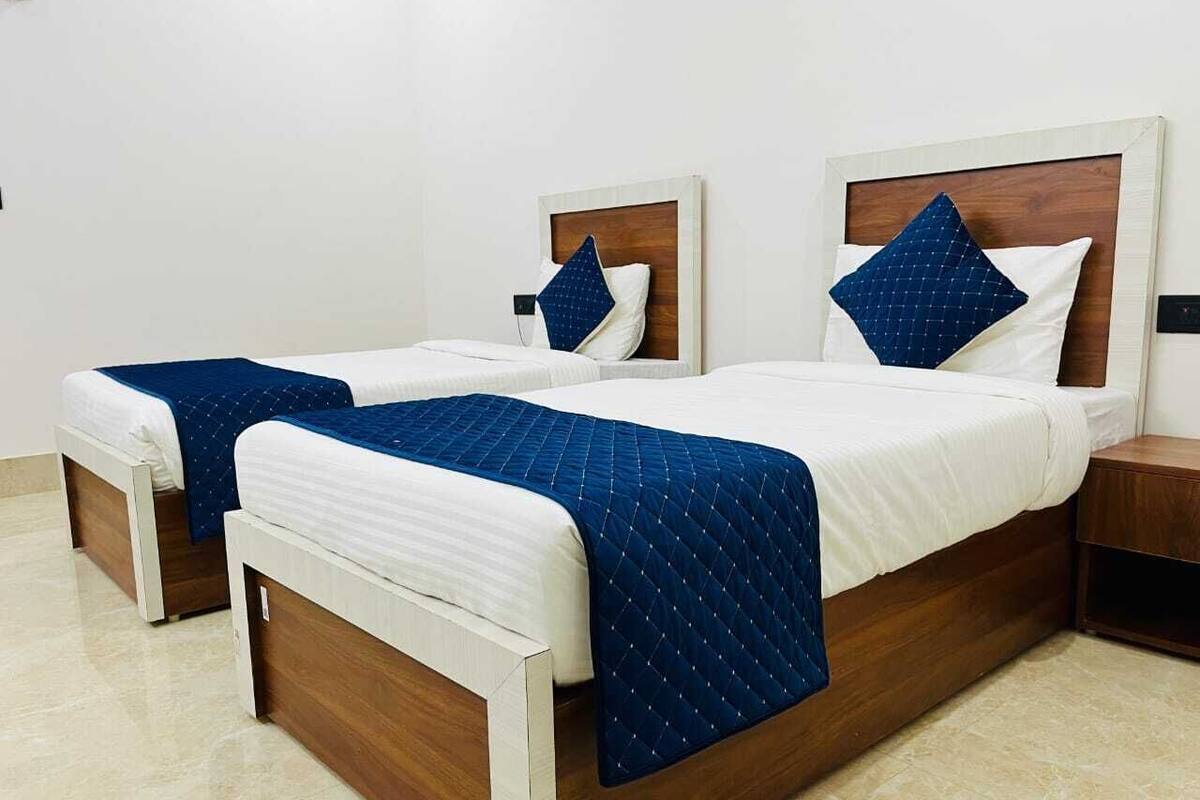 A hotel room with two single beds, each with a wooden headboard and white bedding.