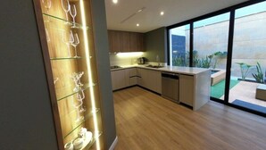 Une cuisine moderne avec des meubles en bois, un meuble-bar intégré et une grande porte-fenêtre coulissante donnant sur un espace extérieur.