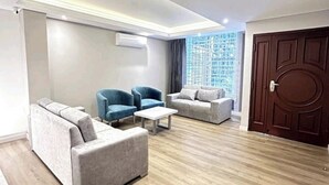 Un salon moderne doté d’un haut plafond, d’un éclairage intégré et d’une grande fenêtre.