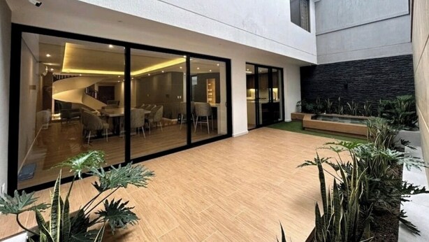 Un intérieur moderne avec un mur en verre, un plancher en bois et des plantes d’intérieur.