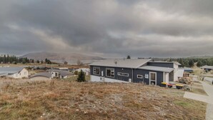 A residential area with houses, a satellite dish, and a view of a lake and mountains in the distance. - Starry Slumber - Your Cozy Retreat in Lake Tekapo (Lake Tekapo)