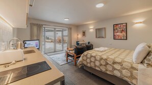 A hotel room with a bed, a desk with a computer, a chair, a small table, and a window with curtains. - Starry Slumber - Your Cozy Retreat in Lake Tekapo (Lake Tekapo)