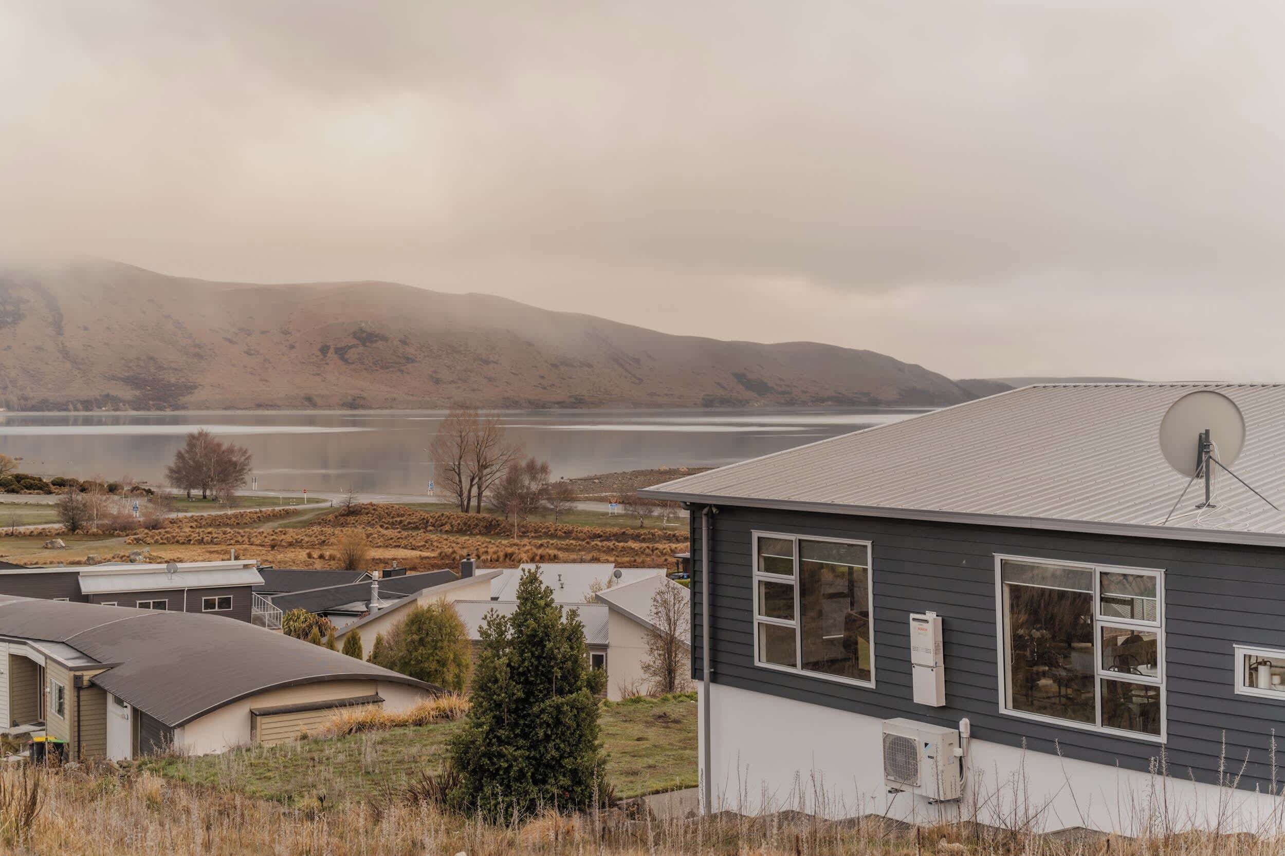 A residential area with houses, a satellite dish, and a lake in the background.