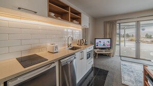 A modern kitchen with a dishwasher, oven, and built-in TV. - Starry Slumber - Your Cozy Retreat in Lake Tekapo (Lake Tekapo)