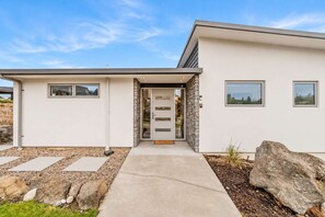 A modern house with a concrete entrance, stone accents, and a clear sky.