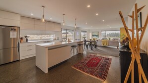 Uma cozinha moderna com uma ilha central, eletrodomésticos de aço inoxidável, luminárias pendentes e vista para o exterior.