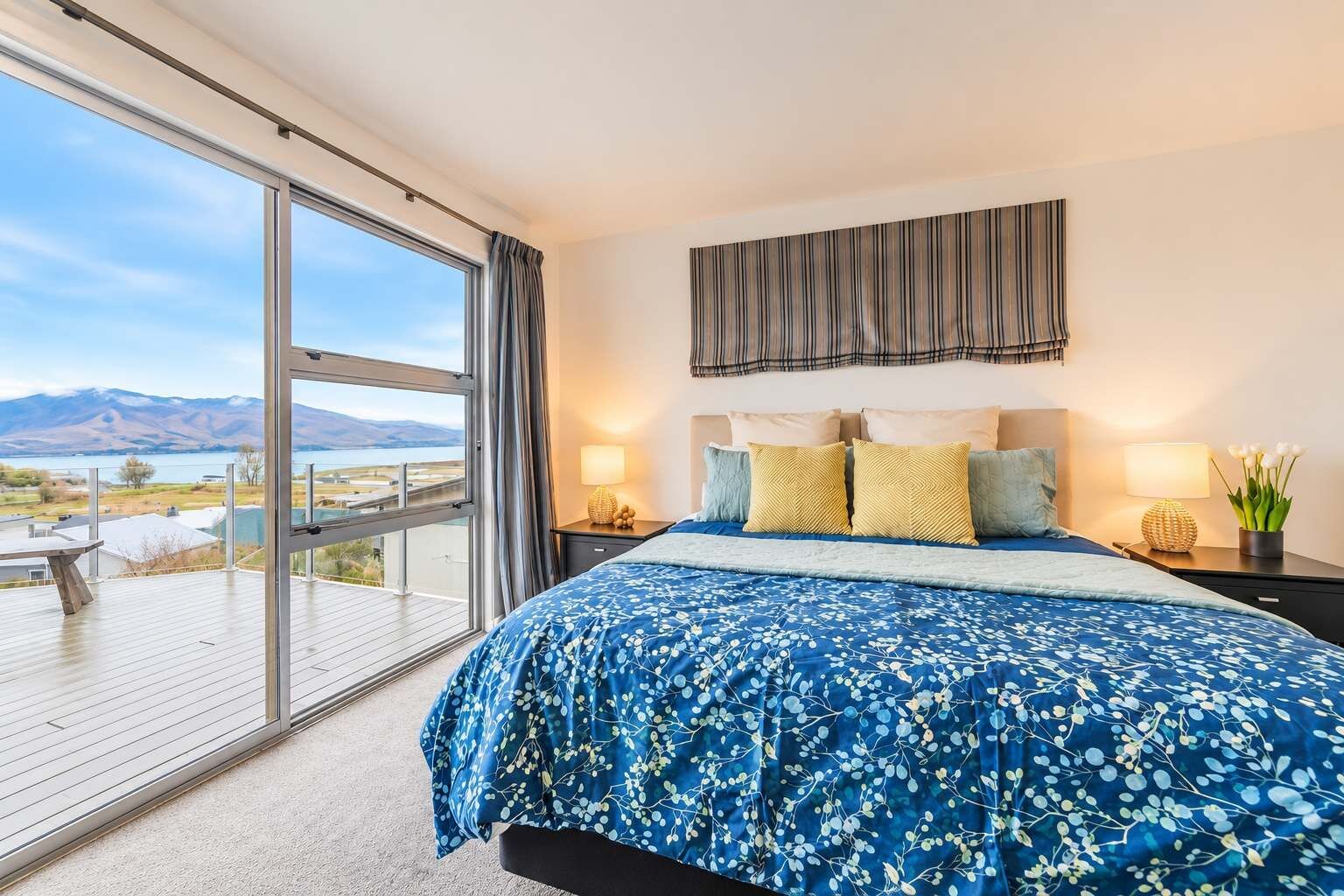 A bedroom with a large bed, a view of a lake, and a balcony.