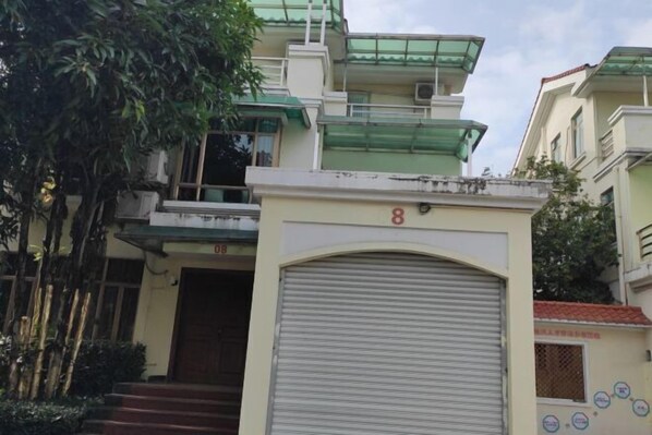 A multi-story building with a green roof, a closed garage door, and a number '8' sign.