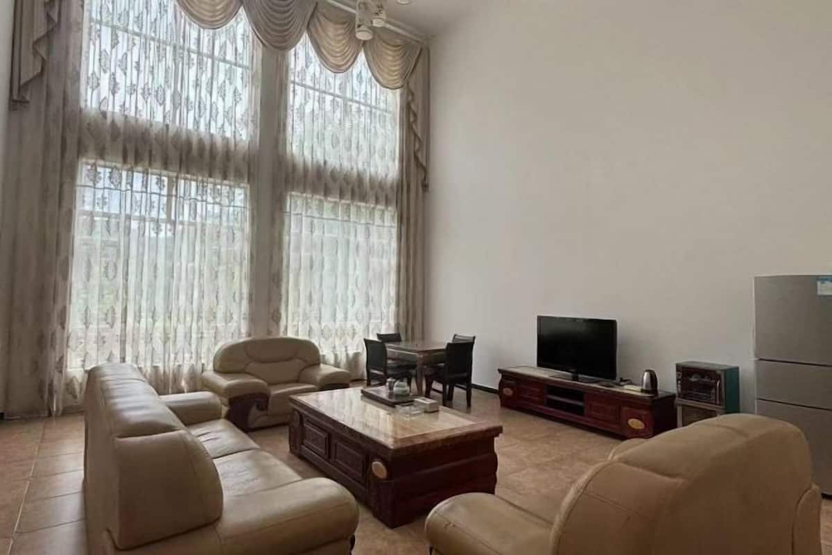 Ein Wohnzimmer mit einer Sofagarnitur, einem Couchtisch, einem Fernseher und einem Kühlschrank.