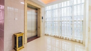 A modern elevator with a marble wall and a framed picture on the left. - Qujiangying Hotel (Shaoguan)
