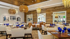 Un espace de restauration moderne avec des murs en bois, des chaises blanches et de la verrerie bleue.