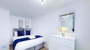 A modern bedroom with a bed, bedside table, and a large mirror. - Ranworth House - Holiday Home in Bedford, Sleeps 5 (Bedford)